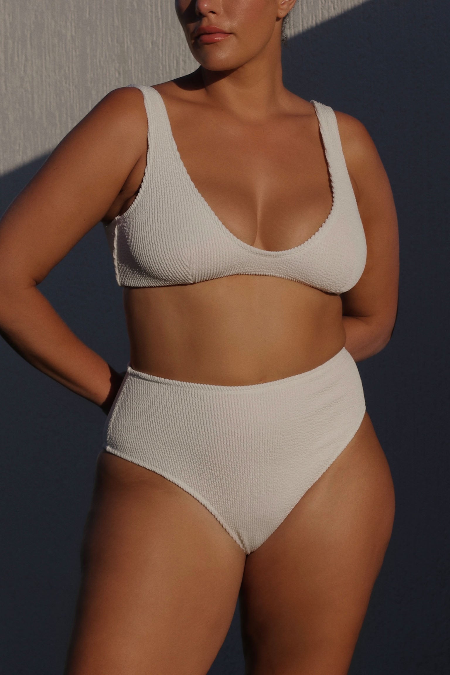 Textured white flattering scoop neck bikini top with thick shoulder straps and adjustable tie-back. 