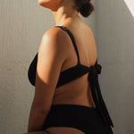 A supportive black textured underwire bikini top with flattering plunge neckline, power mesh lining and adjustable back tie for custom fit. 