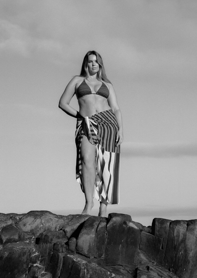 Bree McCann wearing black and brown striped bokumaia bikini top and sarong on the rocks 