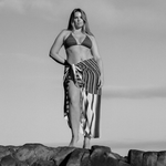 Bree McCann wearing black and brown striped bokumaia bikini top and sarong on the rocks 