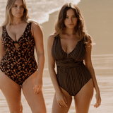 Two models wearing Bokumaia one-piece swimsuits – Gaia One Piece in Mocha Stripe and Noir Hibiscus floral print shown together