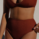 close up of woman wearing brown rust caramel D+ bikini top and high waisted bikini bottom in textured fabric. 