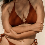 Person wearing a brown triangle bikini against a neutral background