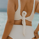 Women wearing white high waisted bikini with adjustable tie back on a beach 